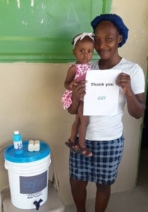 Women and child with chlorine water disinfection kit